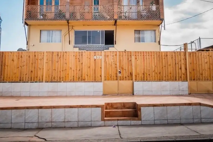 La reja de madera con el número 439 y el portón del hostal, vistos desde la vereda de Av. Arturo Pérez Canto